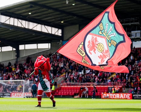 Wrexham mascot, Wrex the Dragon, waves a flag.