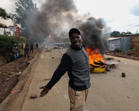 Man stands in front of burning pile of tyres
