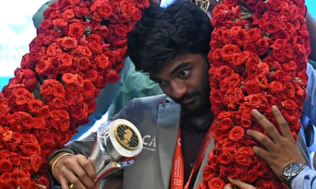 India’s Gukesh Dommaraju holds his World Chess Championship trophy as he is draped with a garland during a press conference in Chennai