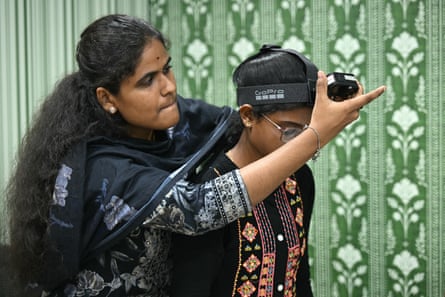 An Indian woman attaches a camera to another woman’s head