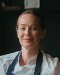 A woman in chef’s whites and a blue apron.