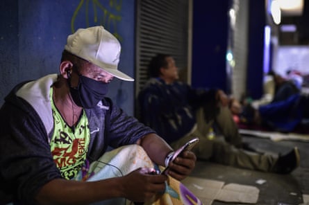 A man checks his phone outside a branch of Caixa Econômica Federal in Belo Horizonte.