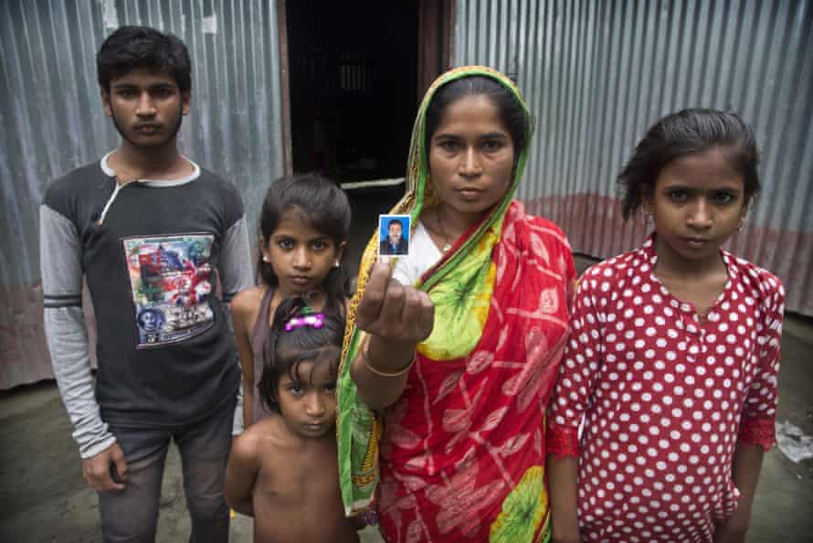 Halimun Nessa, 32, stands with her children and displays a photograph of her husband Rahim Ali, who committed suicide the day before his children were to appear in front of a NRC tribunal in Assam.