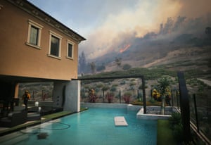Firefighters work as the Silverado fire burns toward a home in Orange county.