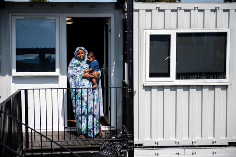 HANWELL, ENGLAND - AUGUST 23: Nasibah Yagoub, 21, poses for a photograph with her 7 month old son Youssef outside the front door to their accommodation at a development of converted shipping containers that are being used as social housing for homeless families on August 23, 2019 in Hanwell, England. Nasibah and her family were moved to one of the containers 6 months ago and is not happy about the accommodation. A new report from the children’s commissioner for England has said that children growing up in such temporary housing are having their health and wellbeing put at risk. A number of temporary housing sites across Britain, including converted office blocks and shipping containers, have come under question in recent months. (Photo by Chris J Ratcliffe/Getty Images)