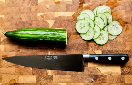 A knife and a sliced cucumber on a wooden board