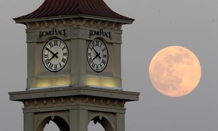 The moon rises behind a clock tower