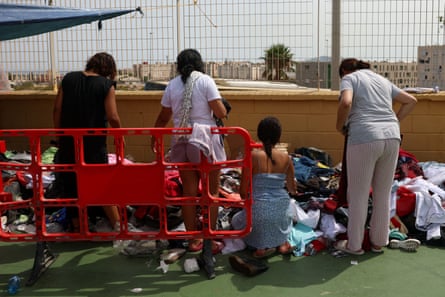 Women and children, backs to camera, picking from donated clothes