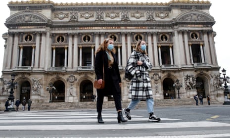 Women wearing masks walk past the closed Opera de Paris in the French capital