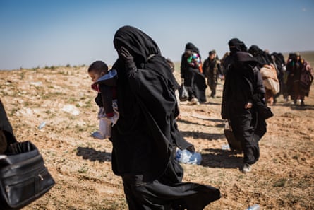 People who fled heavy fighting in the city of Baghuz walk towards a civilian screening point