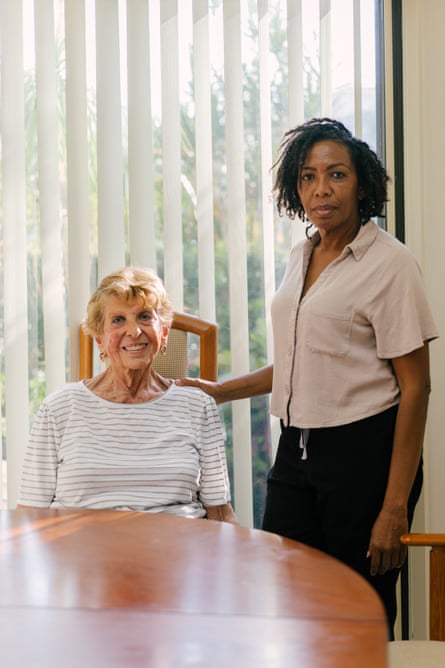 a woman stands next to another woman seated at a table