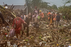 Residents walk across debris floating in floodwaters in a submerged village, as Typhoon Vamco hits in Rodriguez, Rizal province, Philippines.