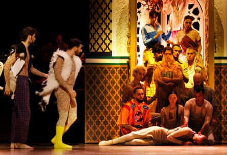 Two men approach a group of men and women sitting and standing above a prostrate figure
