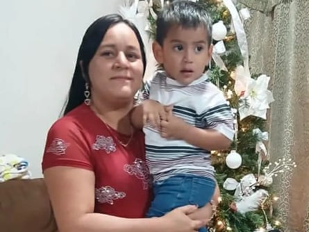 A woman holding a small child and looking at the camera.