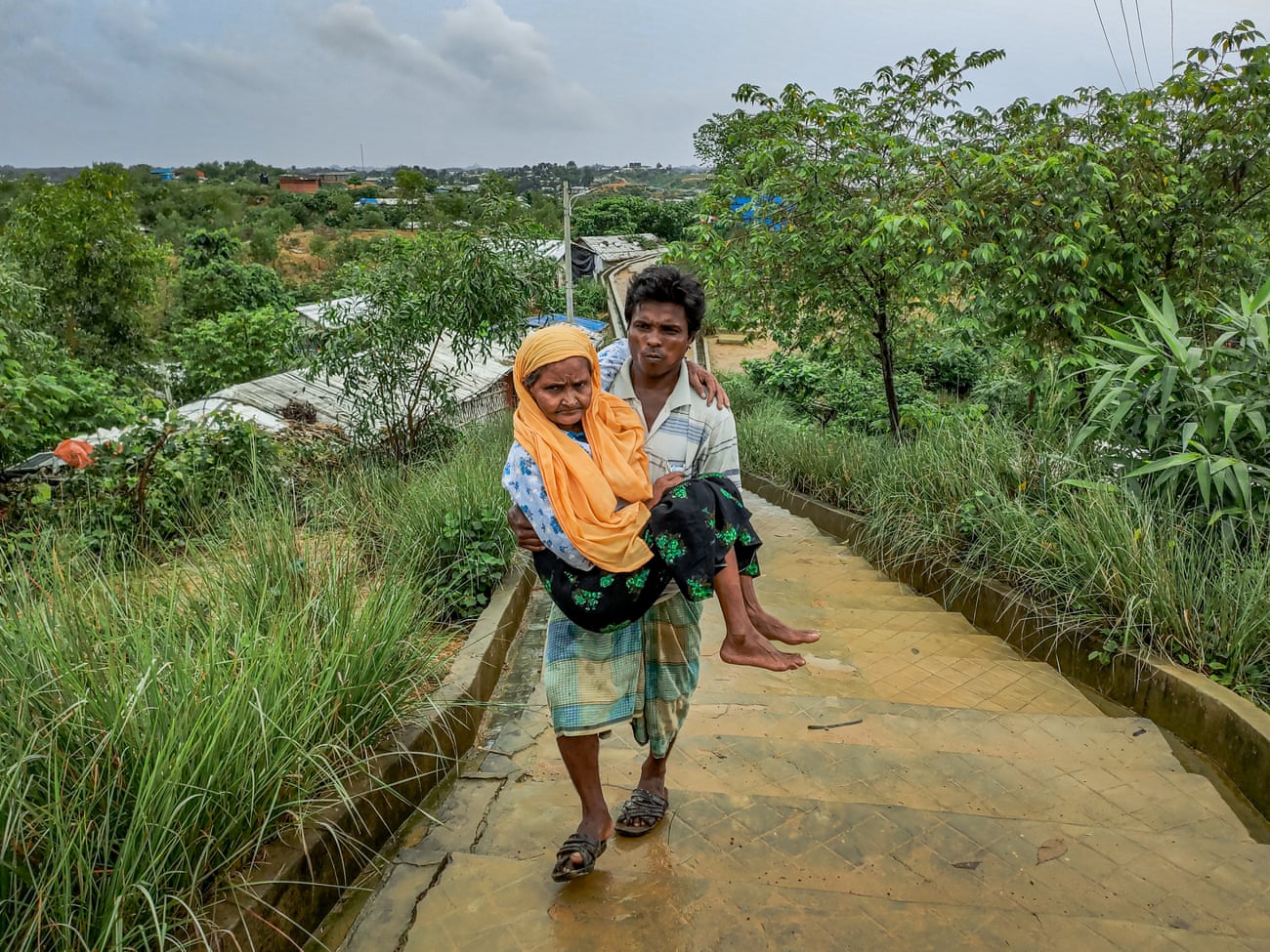 En Rohingya-mann bar sin syke mor til en klinikk i leirene.