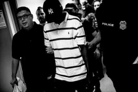 Federal agents hold a man’s arms as they walk to a stairwell