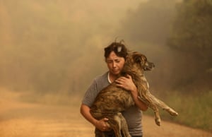 A resident carries a dog as a wildfire burns rural areas around Santa Juana, Chile