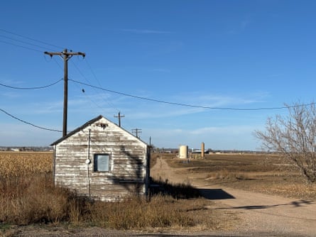 A ramshackle building in a rural area surrounded by flat land.
