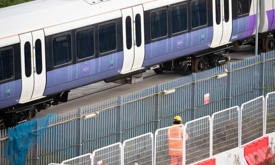 A worker wearing hi-vis clothing passes Crossrail trains at Old Oak Common, west London.