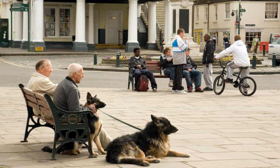 Elderly people and teenagers sitting in separate groups in Wallingford town centre in Oxfordshire, England