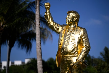 A gold statue of Donald Trump with blue skies and palm trees in the background