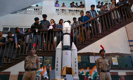 Students stand on stairs behind a model of India’s Chandrayaan-3 spacecraft
