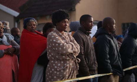 Relatives and local community members look on at the scene.  