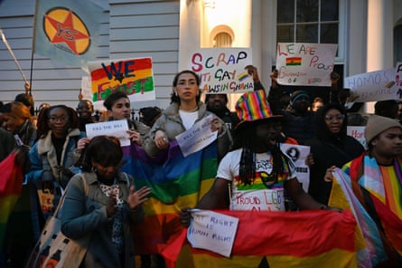 A group of people wrapped in rainbow flags and holding placards.