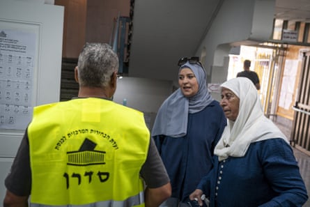 Two female voters talk to an election official at a polling station