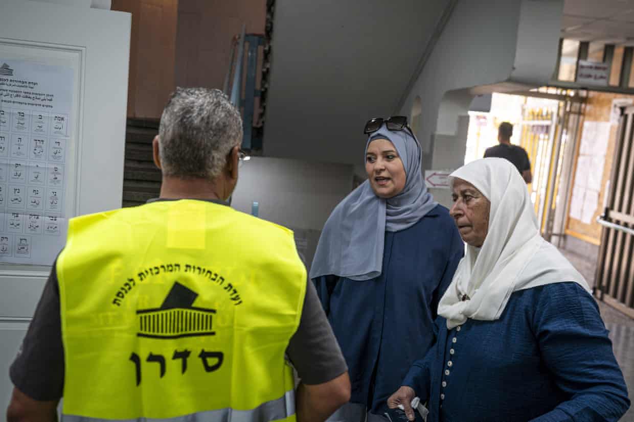 Two female voters talk to an election official at a polling station