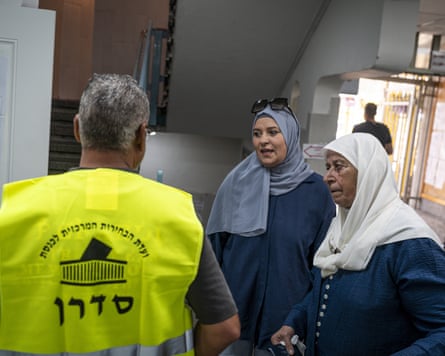 Two women in headscarves talk to an election official