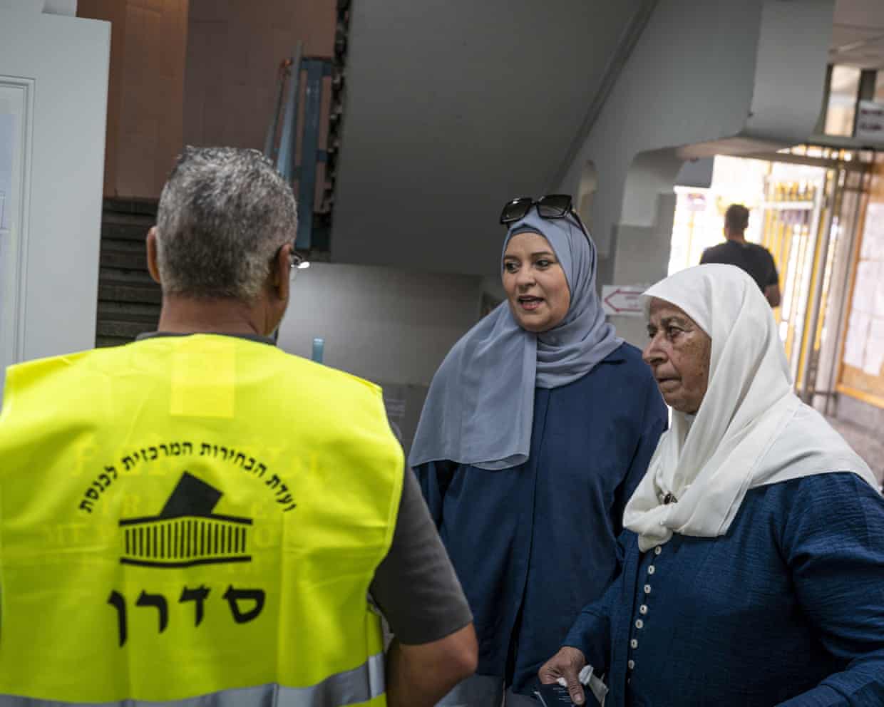 Two women in headscarves talk to an election official