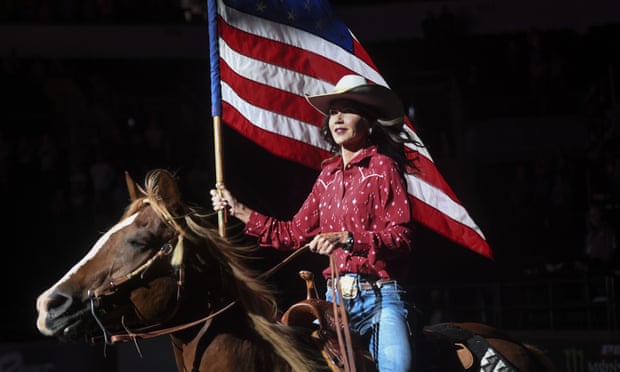 Kristi Noem on horseback holding a US flag