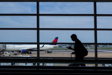 A person walks as a Delta plane is seen in the distance