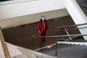 Bugs Mitchell dressed as Joker, looking at the camera from the bottom of a staircase