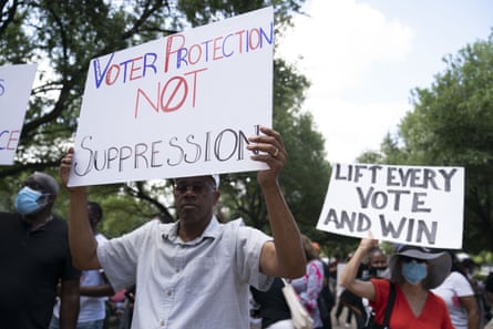 A man holds a sign that reads ‘Voter Protection Not Suppression’ to demonstrate for Voting Rights.
