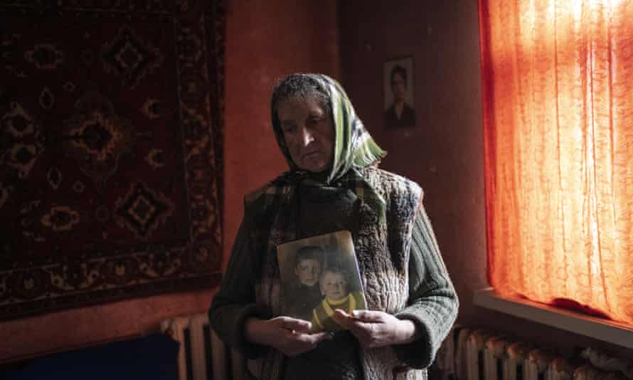 Nadiya Trubchaninova, 70, stands in her bedroom holding a portrait of her sons who were killed by Russian soldiers in Bucha, Ukraine.