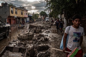 People walk through a street covered in mud and debris