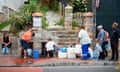 People collect drinking water from pipes fed by an underground spring, in St. James, about 25km from the city centre, on January 19, 2018, in Cape Town. Cape Town will next month slash its individual daily water consumption limit by 40 percent to 50 litres, the mayor said on January 18, as the city battles its worst drought in a century. / AFP PHOTO / RODGER BOSCHRODGER BOSCH/AFP/Getty Images