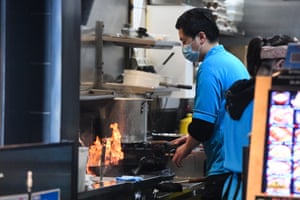 A cook works at a restaurant still open for takeaway in Melbourne on Sunday.