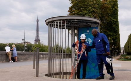 Employees in front of the Eiffel Tower work on access stairs to an underground urban cooling network power station.