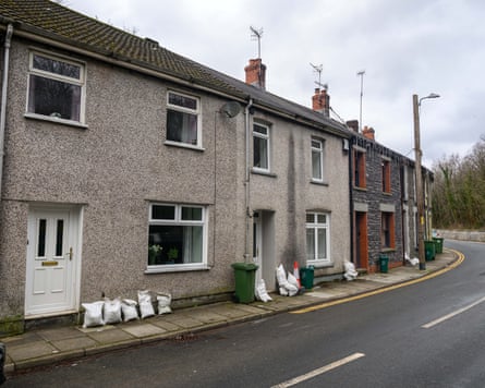 A number of homes on a bend in the road with sandbags outside