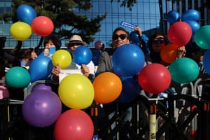 People behind a barricade hold multicoloured balloons