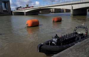 A police boat travels along the Thames next to London Bridge
