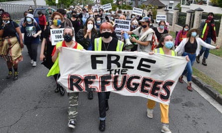 protesters march with a free the refugees sign