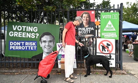 A woman pats a dog as voting signs can be seen at Orange Grove Public School, on 2023 NSW State election day, in Sydney, Saturday, March 25, 2023.