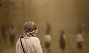 A pedestrian walks with a covered face during a sandstorm in Jerusalem.