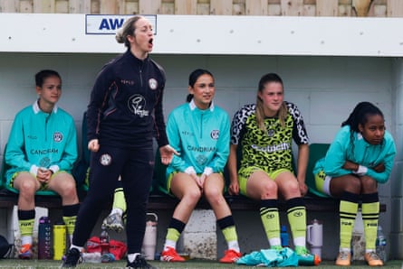 Women football players and their manager at the side of a pitch