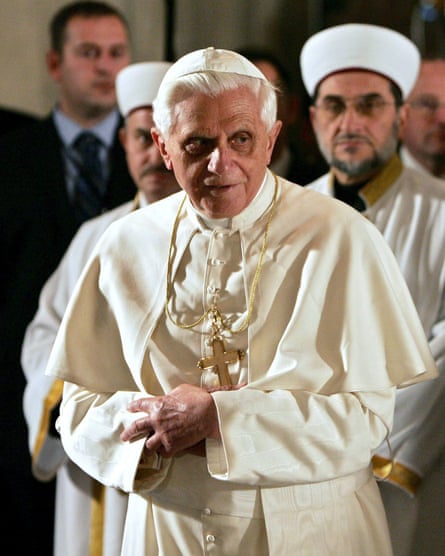 Pope Benedict in papal robes, with hands clasped, visiting a mosque