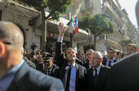 France’s president, Emmanuel Macron, waves at onlookers as he walks with Algeria’s senate president, Abdelkader Bensalah, in Algiers